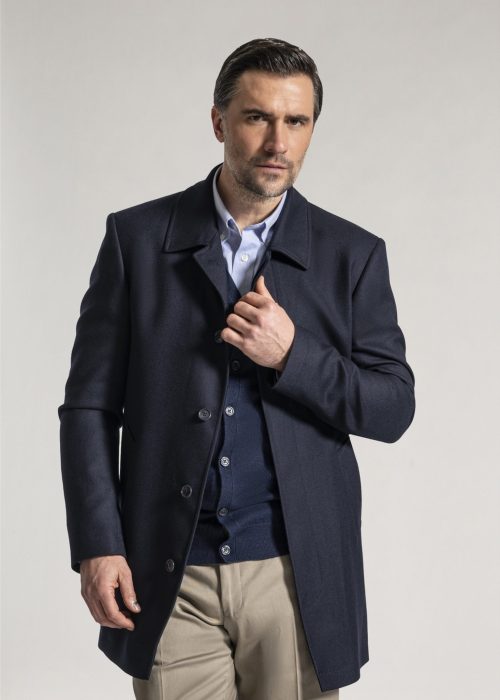 Navy overcoat layered on top of classic oxford shirt and navy merino wool cardigan